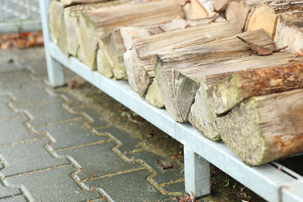 Gestapeld haardhout met goede ventilatie tegen een muur